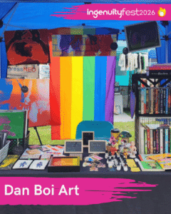 Dan Boi Art - IngenuityFest Vendor - LGBTQ rainbow flag behind a table of art.