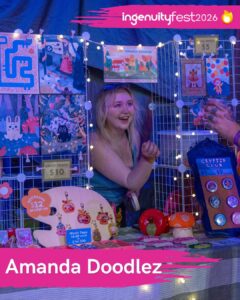 Amanda Doodlez - IngenuityFest Vendor 2026 - Artist at table with original illustrated art in different forms like prints keychains and buttons.