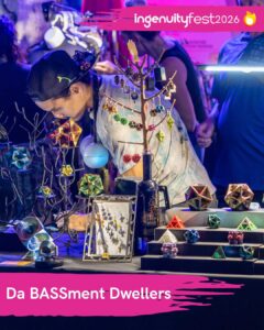 Da BASSment Dwellers - IngenuityFest Vendor 2026 - Artist behind table of small original 3D-printed art and kinetic pieces.