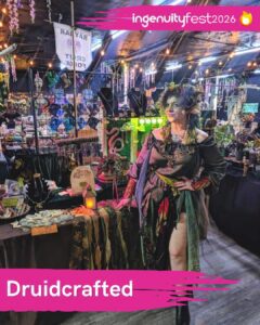Druidcrafted - IngenuityFest Vendor 2026 - Artist standing next to table with druid themed crafts.